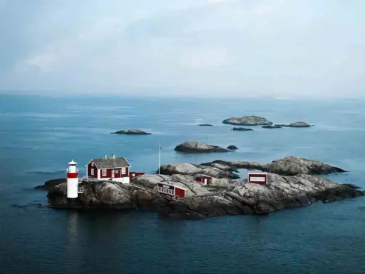 Fyren och röda hus på en klippö bland svenska öar.