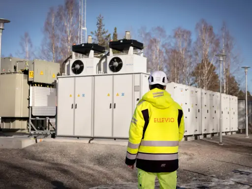 En person i gul jacka står framför en stor fristående batterilagring.