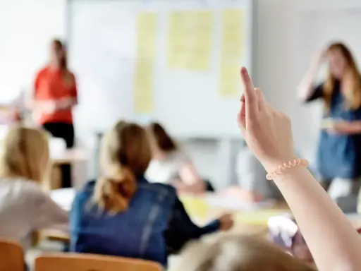 Schülerin hebt die Hand, um eine Frage zu stellen. Vielleicht fragt sie, mit welcher Note man eine 5 ausgleichen kann.