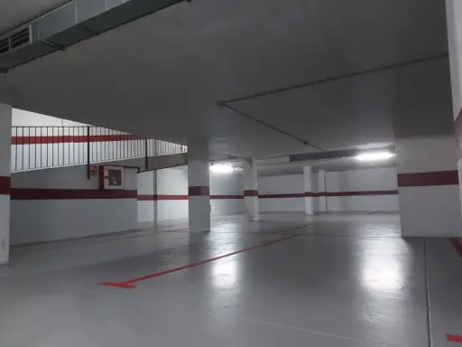 Un garaje particular recién pintado, con líneas rojas en el suelo y paredes blancas con franjas rojas.