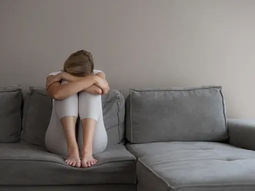 Kobieta z depresją siedzi skulona na kanapie, przygotowując się do komisji lekarskiej ZUS. Co mówić, by uzyskać pomoc?