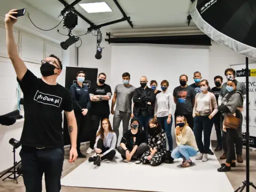Grupa entuzjastów fotografii na zajęciach w szkole fotografii. Uczestnicy pozują do wspólnego zdjęcia w studiu.