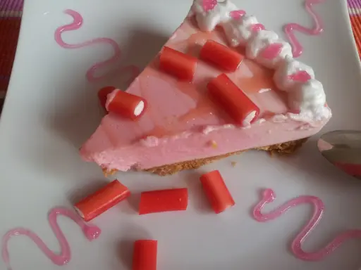 Deliciosa tarta de regaliz rojo con crema rosa y adornos de regaliz.