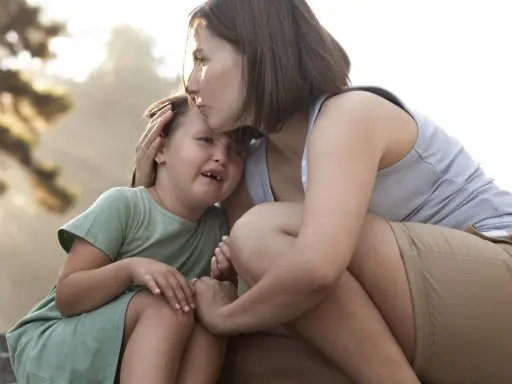 Madre consola la figlia che piange, un abbraccio che mostra le diverse tipologie di attaccamento sicuro e amorevole.