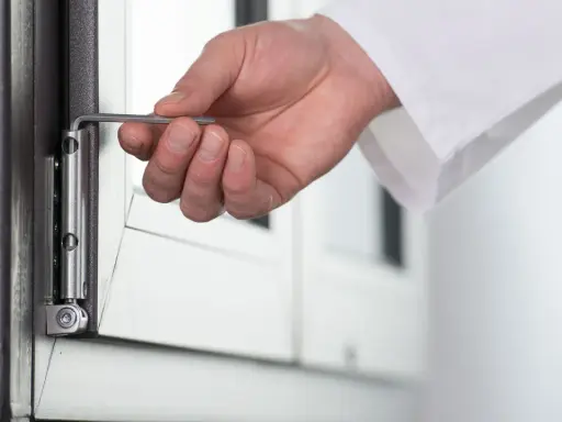 Dłoń z kluczem imbusowym dokonuje regulacji zawiasów drzwi, zapewniając ich płynne działanie.