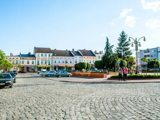 Rynek w Krapkowicach z kolorowymi kamienicami i brukowaną nawierzchnią. Atrakcje miasta widoczne w tle.