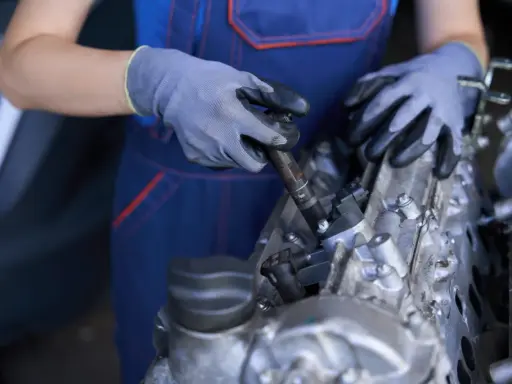Mecánico con guantes trabajando en un motor, mostrando componentes como inyectores y partes del cigüeñal.