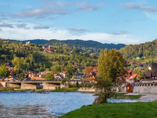 Widok na malownicze ulice w Szczawnicy, z domami na zboczach gór i rzeką w tle.