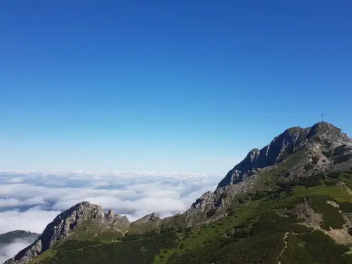 Giewont wysokość 1894 m n.p.m. widoczna z grani, morze chmur poniżej, błękitne niebo.