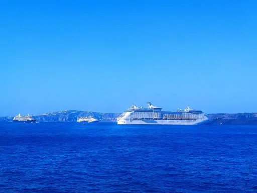 Grandi navi da crociera Royal Caribbean navigano in acque blu, con isole sullo sfondo.