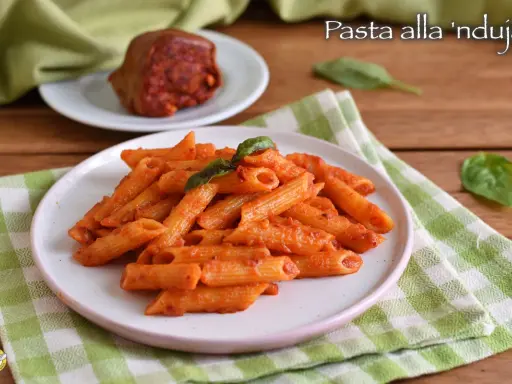 Piatto di penne al sugo rosso piccante, condite con nduja calabrese e basilico fresco.