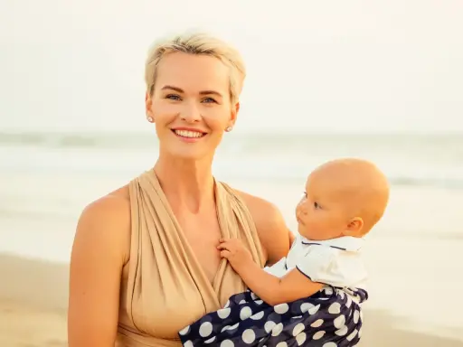 Uśmiechnięta mama z dzieckiem na plaży. Czas na nowe etapy, nawet jeśli to nagłe odstawienie od karmienia piersią.