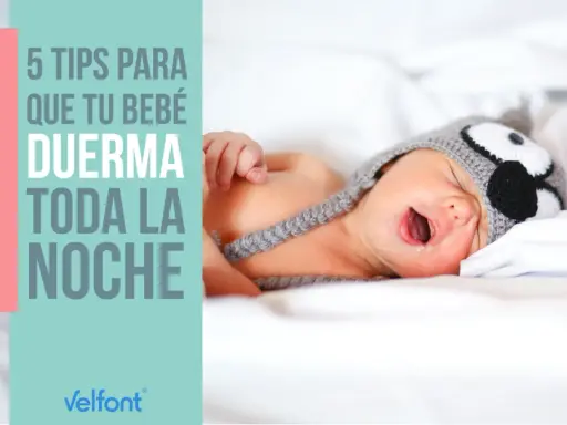 Un bebé con gorro de búho, con la boca abierta, en la cama. 5 consejos para que tu bebé duerma toda la noche.