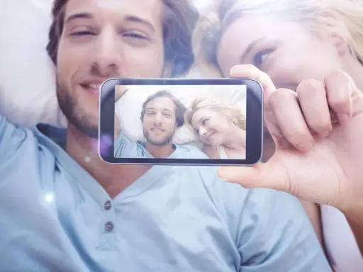 Para widzi na ekranie telefonu siebie, uśmiechnięci i blisko. To piękne objawy zauroczenia.