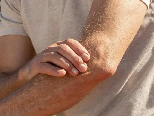 Mann hält seinen Arm, da er Ellenbogen Schmerzen beim Strecken hat.