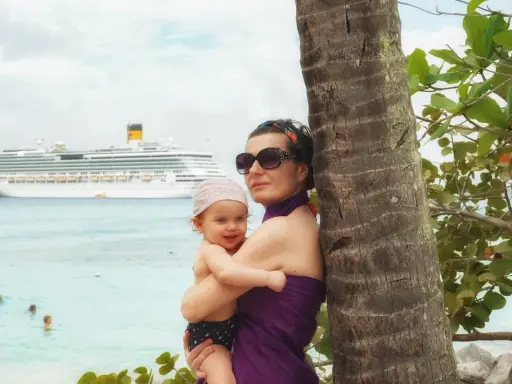 Mamma e bimbo abbracciati vicino a una palma, con una nave da crociera all'orizzonte. Una splendida posizione costa pacifica.