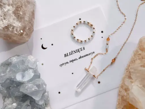 Delikatna biżuteria z kamieniami, w tym akwamaryn, otoczona surowymi kryształami.