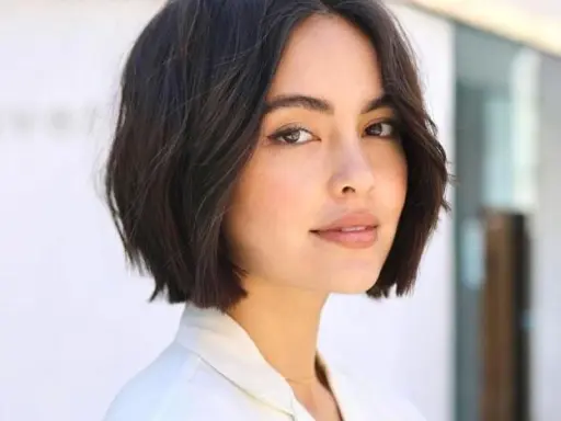 Mujer con un moderno corte de pelo bob oscuro y ondulado, luciendo un estilo chic y juvenil.