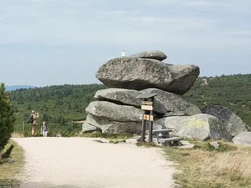 Wielkie głazy i ławka przy szlaku przyjaźni polsko czeskiej. Turyści podziwiają krajobraz.