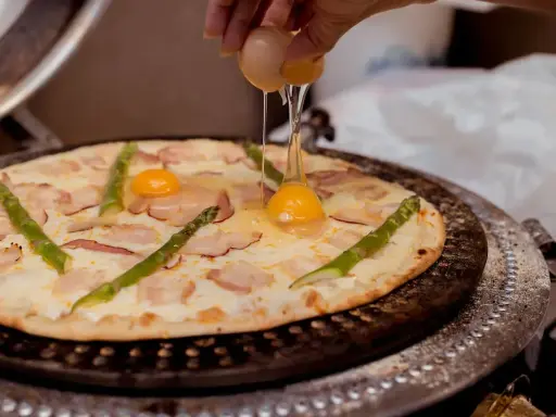 Na pizzę z boczkiem i szparagami dodawane jest jajko.