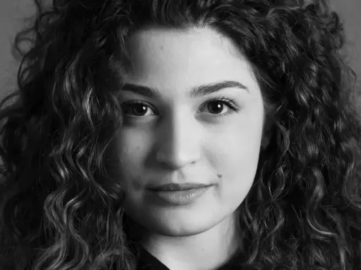 Primo piano di una giovane donna con capelli ricci, un esempio di diversi tipi di ritratto che catturano espressioni uniche.