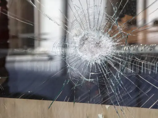 Une étoile de verre brisé se propage à travers la vitre, révélant un monde flou derrière.