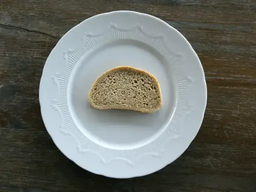 Jeden plasterek chleba tostowego na białym talerzu. Zastanawiasz się nad jego kcal?