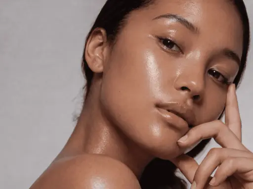 Rostro de mujer con piel glowy, hidratada y radiante. Su mano acaricia suavemente su barbilla.