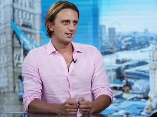Nikołaj Storonski w różowej koszuli, na tle panoramy Londynu z Tower Bridge.