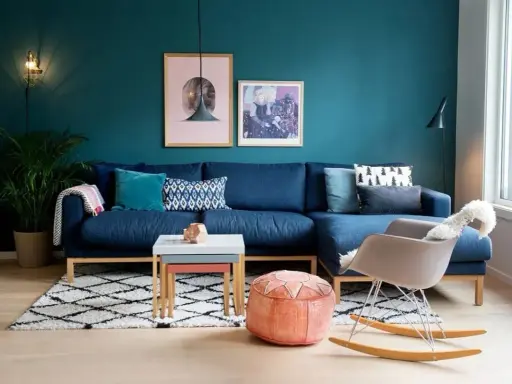 Un accogliente salotto con divano blu, tappeto a rombi e pareti color ral ottanio.