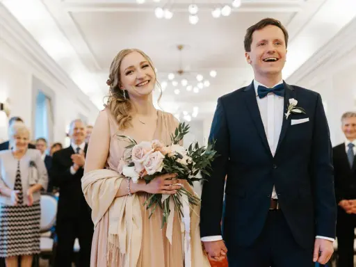 Para młoda uśmiecha się radośnie, trzymając bukiet. Złożyli wniosek o ślub cywilny i są gotowi na ceremonię.