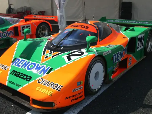 El icónico Mazda 787B, con su distintivo diseño naranja y verde, listo para la carrera.