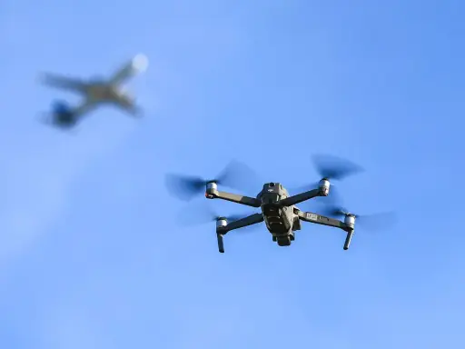 Drohne fliegt im Himmel, ein Flugzeug im Hintergrund. Wichtig: Drohne Haftpflicht für sichere Flüge.