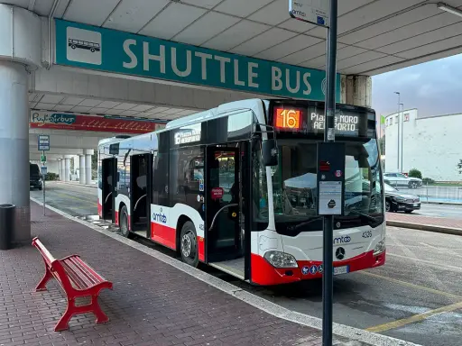 Autobus wahadłowy na przystanku lotnisko. Czerwona ławka czeka na pasażerów.