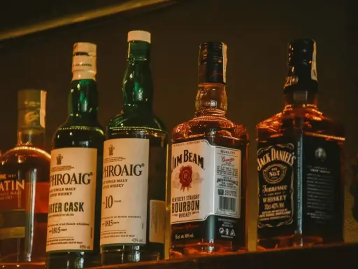 Rząd butelek whisky: Laphroaig, Jim Beam i Jack Daniel's.