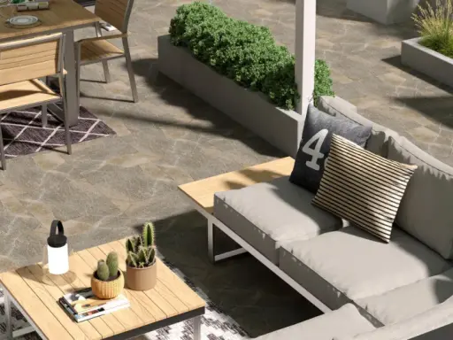 Un elegante giardino pavimentato moderno con divano, tavolo da pranzo e piante.