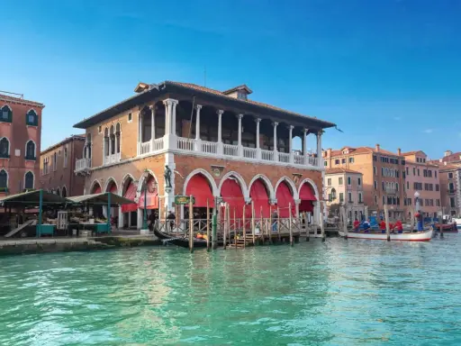 Le marché du Rialto à Venise, avec ses étals colorés et ses gondoles sur le Grand Canal.