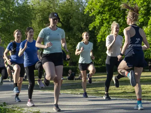 Grupp kvinnor tränar löpning i parken, ett intensivt backintervaller pass.