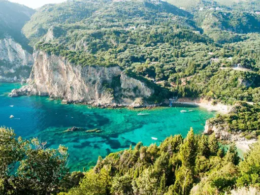 Baia verde smeraldo a Corfu, perfetta per una vacanza con bambini. Scogliere imponenti e acque cristalline invitano al gioco e all'esplorazione.