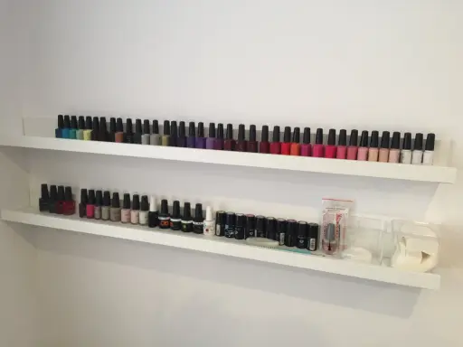 Dwie białe półki wypełnione po brzegi kolorowymi buteleczkami. To idealna półka na lakiery dla każdej miłośniczki manicure.