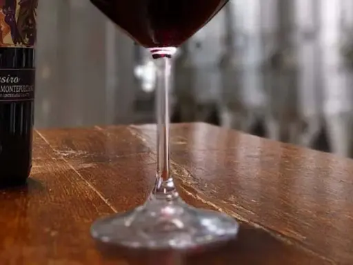 Bottiglie di Vino Nobile di Montepulciano e un calice di vino rosso, pronti per una degustazione vini toscana.