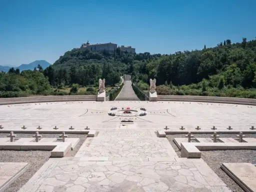 Cmentarz żołnierzy polskich, gdzie jest Monte Cassino. Monumentalny widok na wzgórze z opactwem, schody, krzyże i kamienne nagrobki.