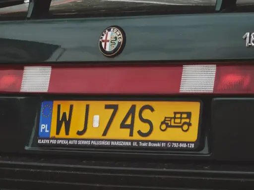 Zielona Alfa Romeo z żółtą rejestracją WJ-74S. Na tablicy widnieje symbol starego samochodu.