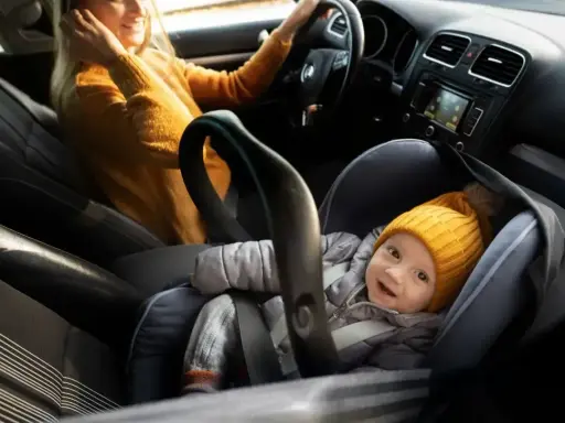 Uśmiechnięte dziecko w foteliku z systemem isofix na przednim fotelu, gotowe na podróż z mamą.