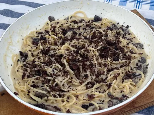 Spaghetti cremosi con olive nere e una spolverata di cacao amaro, un'originale pasta alla cenere.