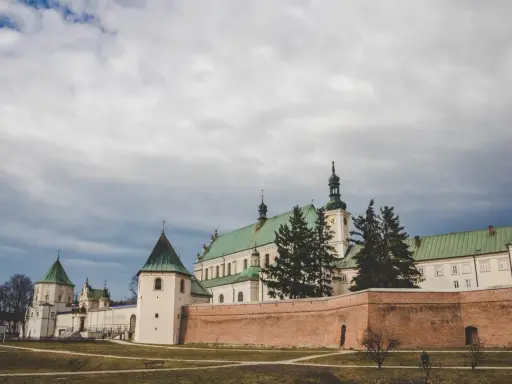 Klasztor Bernardynów w Leżajsku, jedna z głównych atrakcji miasta, z zielonymi dachami i ceglanym murem.