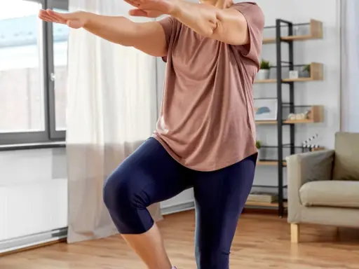 Frau macht Oberschenkel Training ohne Kniebelastung. Sie steht auf einem Bein, das andere angewinkelt.
