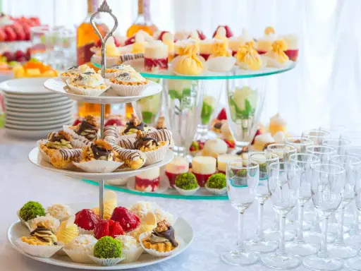 Un buffet de hors d'œuvre varié avec des mini-tartes, des éclairs au chocolat et des fruits frais, prêt à ravir les invités.
