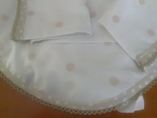 Patrones de sábanas para cochecito de bebé hechas a mano con lunares rosados y borde de encaje.