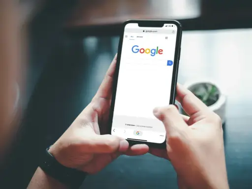 Ręce trzymające smartfon z otwartą wyszukiwarką Google. Szukasz informacji, jak usunąć konto Google z telefonu po resecie?